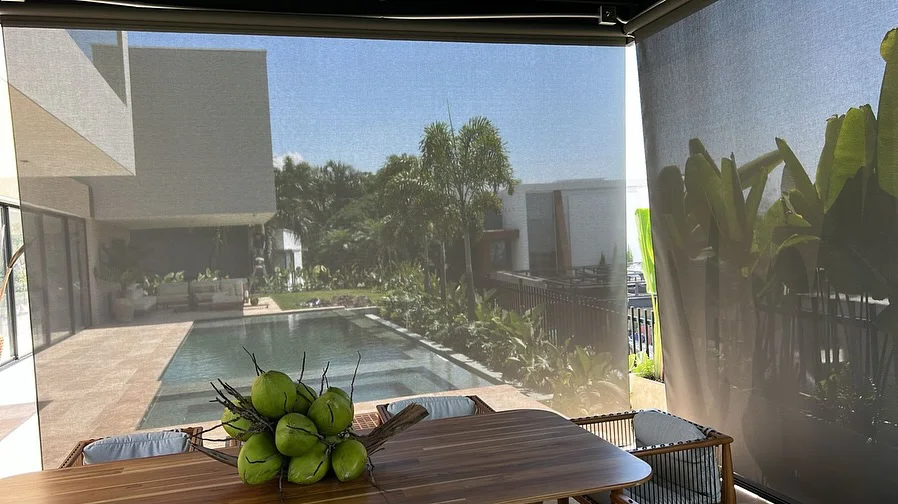 Toldos verticales enrollables protegiendo comedor exterior junto a la piscina en Cali